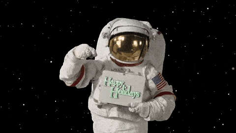 Astronaut floating in space suit pointing to Happy Holidays sign